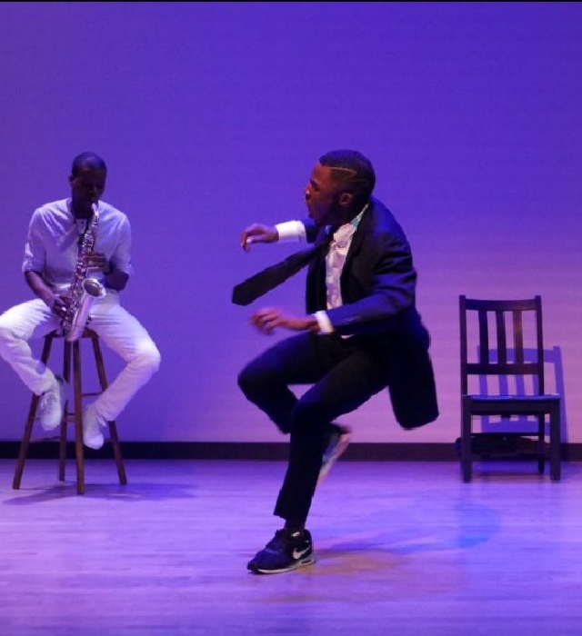Tristan Parks dancing in front of a person playing a sax.